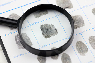 Fingerprints card police form on A4 tablet lies on office table with pen and magnifying glass close...