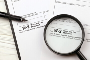 IRS Form W-2 Wage and Tax Statement blank on A4 tablet lies on office table with pen and magnifying...