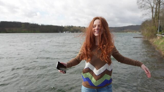 Basking in autumn sun, red-haired woman enjoys serene jetty