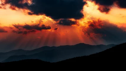 Poster Beautiful sunset sky with dramatic sun rays over a mountain landscape © Wirestock