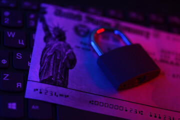 United States Treasury refund check or stimulus bill with small padlock on computer keyboard close...