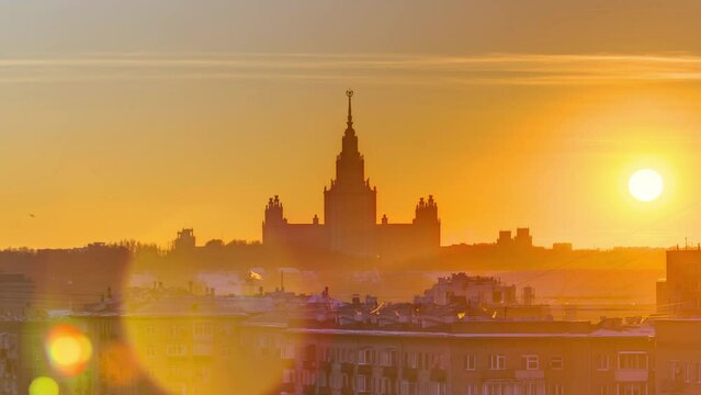 Timelapse of a winter sunset over Moscow State University, captured from a top view along Komsomolskiy Avenue, with rooftops in the foreground