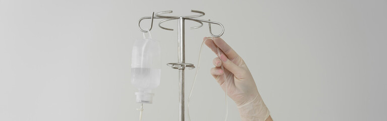 Doctor's hand regulating IV infusion system in medical center. Healthcare concept