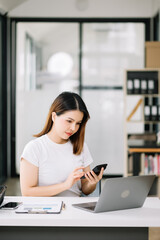 Fototapeta premium Confident Asian woman with a smile standing holding notepad and tablet at office..