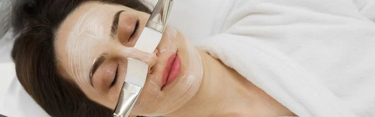 Papier Peint photo Lavable Salon de massage Cosmetologist applying mask on clients face with a brush in spa salon. Wellness center