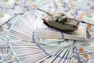 Toy tank on US hundred dollar bills banknotes close up. The concept of war costs, military spending...