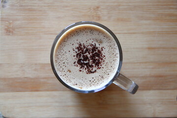 Transparent mug of cappuccino with delicate froth with chocolate top view