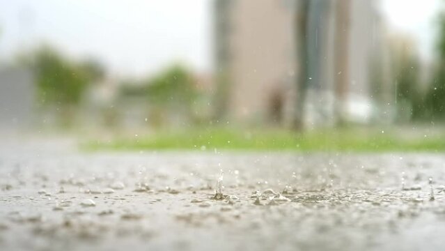 Atmospheric video of rainstorm in a city. Heavy rain and splashes puddles taken from low point. Large drops break on the pavement. Slow motion
