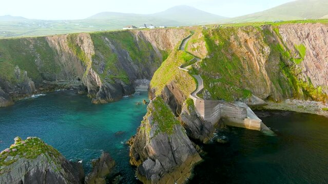 Dunquin or Dun Chaoin pier, Ireland's Sheep Highway. Aerial view of narrow pathway winding down to the pier, ocean coastline, cliffs. Popular iconic location on Slea Head Drive and Wild Atlantic Way.