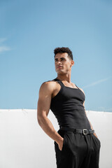 Fototapeta premium muscular young cuban man in black sleeveless t-shirt and pants posing in Miami, south beach