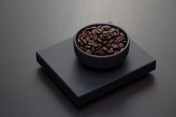 Roasted coffee beans on a black digital scale.