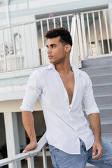 cuban man in white shirt and jeans looking away on urban street in Miami