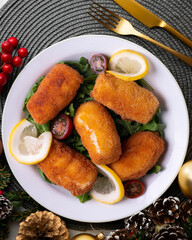 Fish croquettes. Traditional tapas of the coastal areas in Spain. Christmas food served on a table decorated with Christmas motifs.