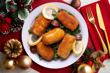 Fish croquettes. Traditional tapas of the coastal areas in Spain. Christmas food served on a table decorated with Christmas motifs.