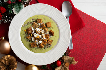 Artichoke cream with bread croutons. Typical Spanish vegan tapas.. Christmas food served on a table decorated with Christmas motifs.