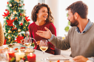 Couple speaking while having Christmas dinner with friends at home