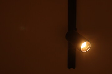 A Black Aluminum Track Light illuminated by a Track spot light on the white ceiling directing...