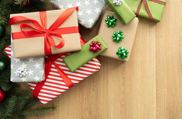 Wrapped Christmas gifts stacked under the tree. Gift boxes in wrapping paper, placed on wooden floor, top view from above. Pile of festive presents. Winter holiday season composition with copy space.