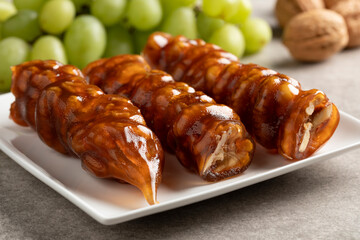 Plate with traditional Cevizli Sucuk, Turkish Churchkhela with walnuts and molasses close up