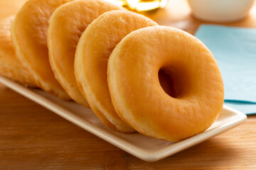 Plate with a row of tasty sweet traditional donuts close up