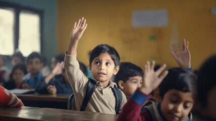 Small indian boy kid in school classroom raising hand up to answer teacher.

