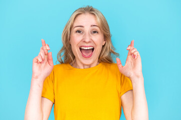 Excited woman with crossed fingers and opened mouth - obrazy, fototapety, plakaty
