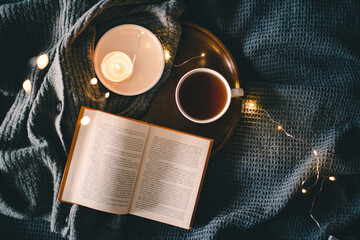 Cozy night with reading book and drinking coffee in bed close up top view. Hygge home atmosphere....