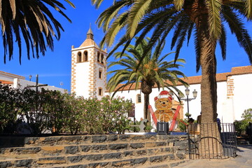 Christmas Canary Islands. A snowman with skis sits in front of the church in Betancuria - Powered by Adobe