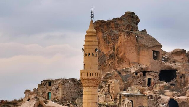 Aerial: Drone Upward Shot Of Tall Old Castle In Cavusin Village With Cave Houses Against Cloudy Sky - Cappadocia, Turkey