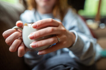 a young white woman with a ring on her finger holding a mug