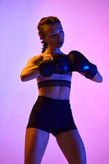Energetic, boxer girl, female professional sportsman in action against white studio background in neon light. power and determination.