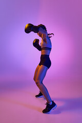 Fototapeta na wymiar Fierce and confident, determined boxer girl, professional sportsman posing against gradient studio background in violet neon light. Concept of individual sport.