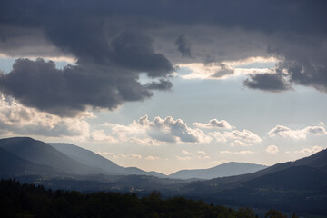 Clouds over the mountains and a valley in suspenseful lighting