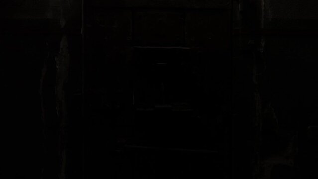 This stock video shows heavy wooden doors with metal bolts in the prison, which are illuminated by red lamps. This video will decorate your projects related to prisons, repressions, quests.