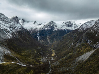Fototapeta na wymiar aerial view over valley in mountains with snowy peaks with flowing river