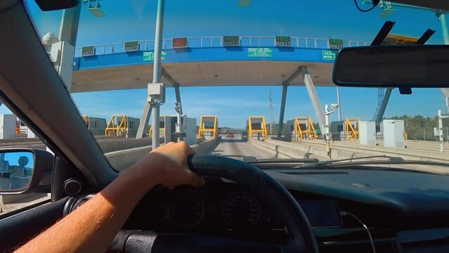 ISTANBUL, TURKEY - SEPTEMBER 2, 2023: First-person view of car e through windshield passing automatic toll terminal in turkey HGS. Driver's hands holding steering wheel.