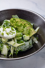 Delicious salad with poached egg, avocado, and cucumber