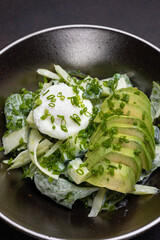 Delicious salad with poached egg, avocado, and cucumber