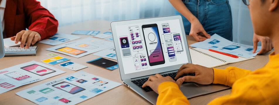 Panorama banner of startup UX developer or company employee design user interface or UI prototype for mobile application or website software with software display on laptop monitor in office. Synergic