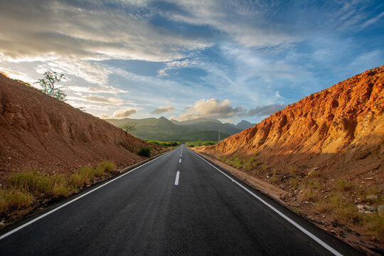 Sunrise in the desert. Tour of a desert island, full of xeric vegetation. Cactus and red earth. Mountains, clouds and sun