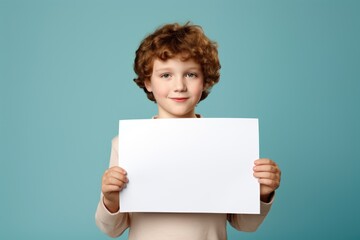 a handsome boy holding a blank placard sign poster paper for mock up in his hands