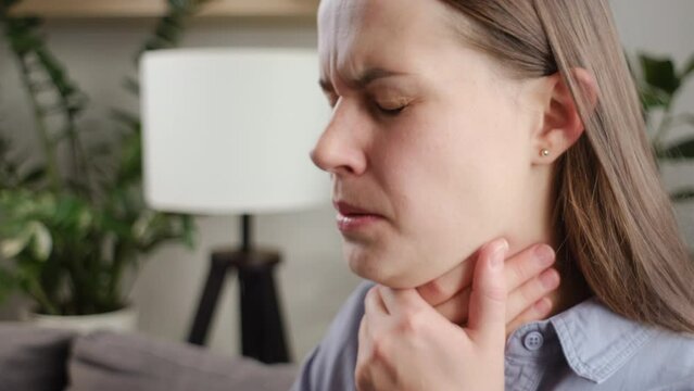 Unhealthy sad young woman have sore throat cough symptom and feel sick from virus or bacteria infection influenza by touching neck and hard to swallow and drink water, experience loss of voice