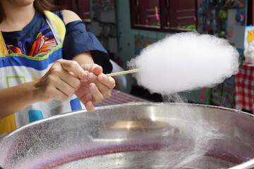 Woman making white cotton candy in cotton candy machine