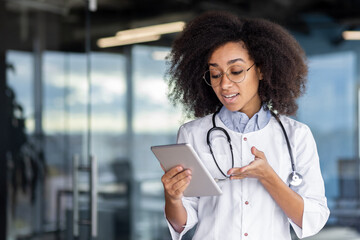 A young female doctor holds a tablet computer in her hands, a woman in a white medical coat...
