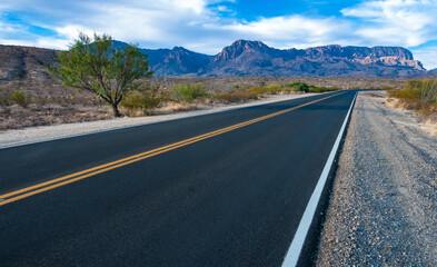Smooth asphalt road in the Texas desert in Big Bend NP, landscape with mountains in the background