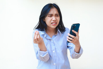 angry asian woman wearing blue stripes shirt holding mobile phone raising palms looks annoyed standing over isolated white background