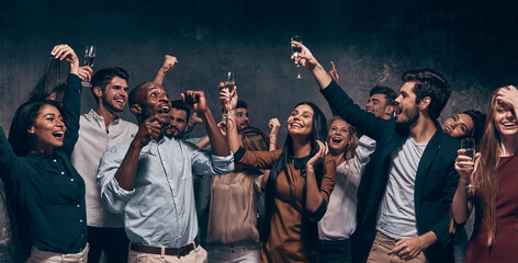 Fototapeta na wymiar Happy young people toasting with champagne and dancing while enjoying celebration in night club