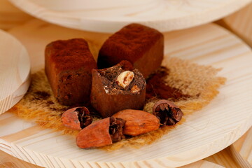 Primo piano di tartufi di cioccolato extrafondenti con nocciole e fave di cacao su sfondo di legno