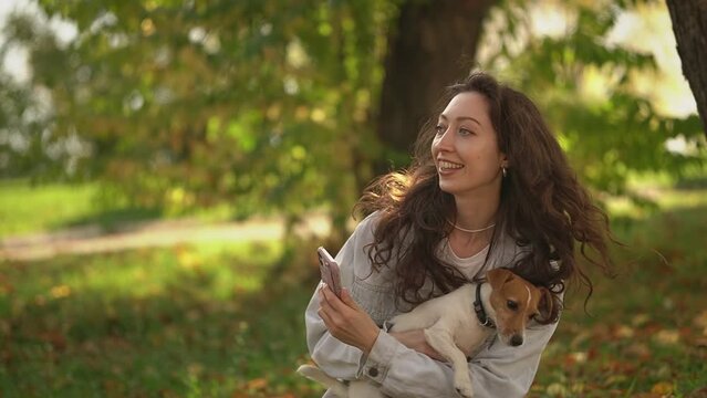 woman and dog. a woman takes a photo on a smartphone. a woman walks her dog in the park. Slow motion video. High quality video in 4K format.