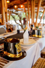 Golden colored new year's hats with glittery decorations lying down on dinner table in restaurant ready for celebration
